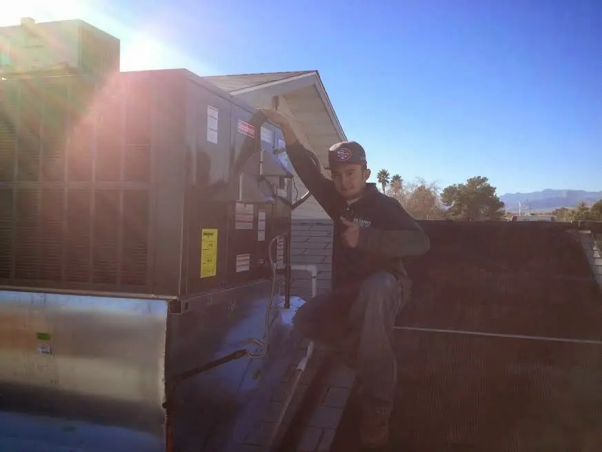 HVAC technician performing Boiler Repair on a rooftop unit in Ennis